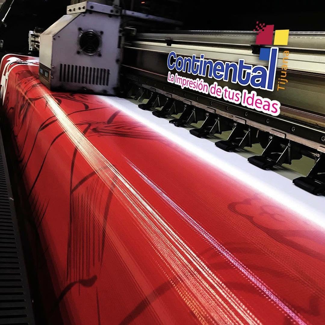 Impresora de gran formato imprimiendo una lona roja